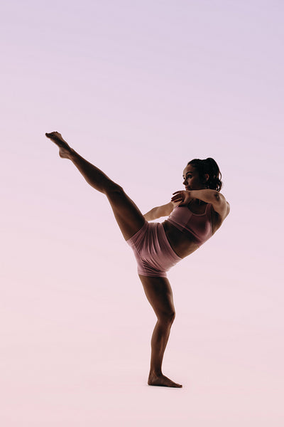Skilled female gymnast practicing her routine with an acrobatic kick