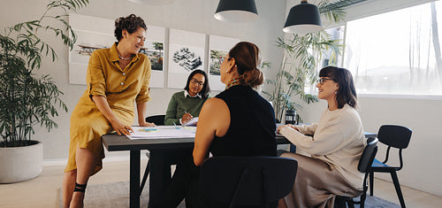 Four professional women discussing a project in a modern office setting
