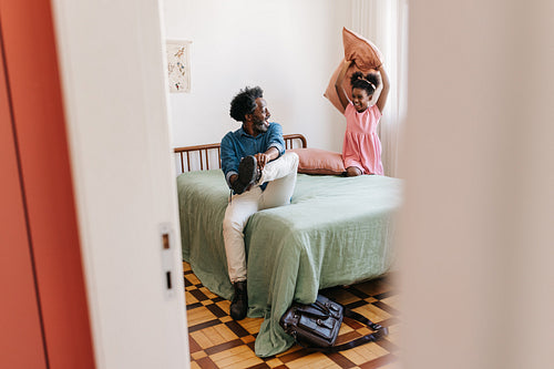Playtime after work: Girl starting a fun pillow fight with her dad