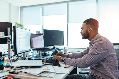 Businessman working on computer at his desk in office.
