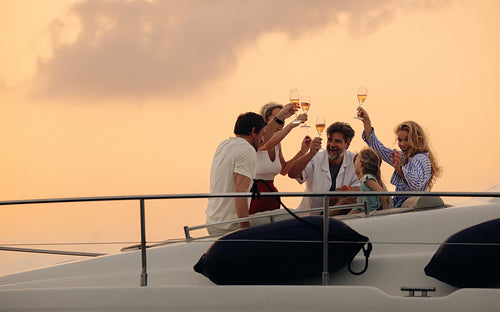 Wealthy family toasting to health and happiness on a luxury boat at sunset