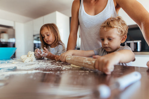 Kids making cookies with mother in kitchen