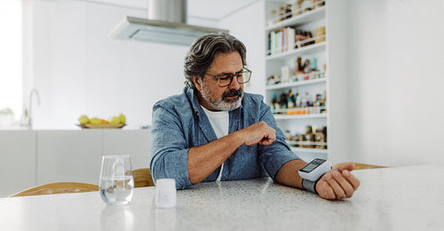 Senior man checks blood pressure at home