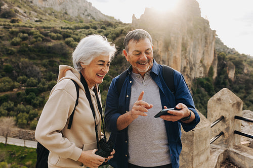Carefree senior couple having a video call while hiking outdoors