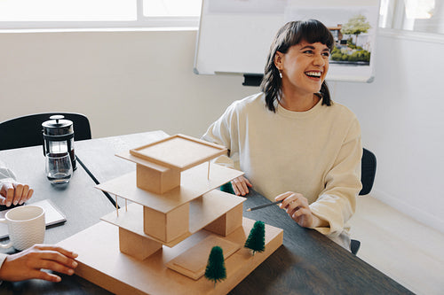 Female project manager working on architectural model with team in office