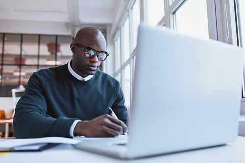 Handsome young businessman writing notes