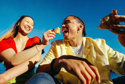 Pizza brings friends together by the waterfront under a clear summer sky