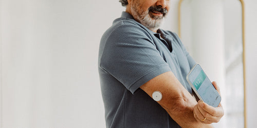 Senior man scans glucose monitor with smartphone