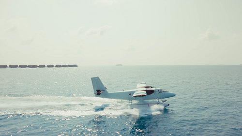 Seaplane gracefully glides across the stunning turquoise ocean arriving at a luxury island resort