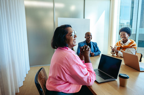 Cheerful Indian female professional in pink shirt laughing during a business meeting