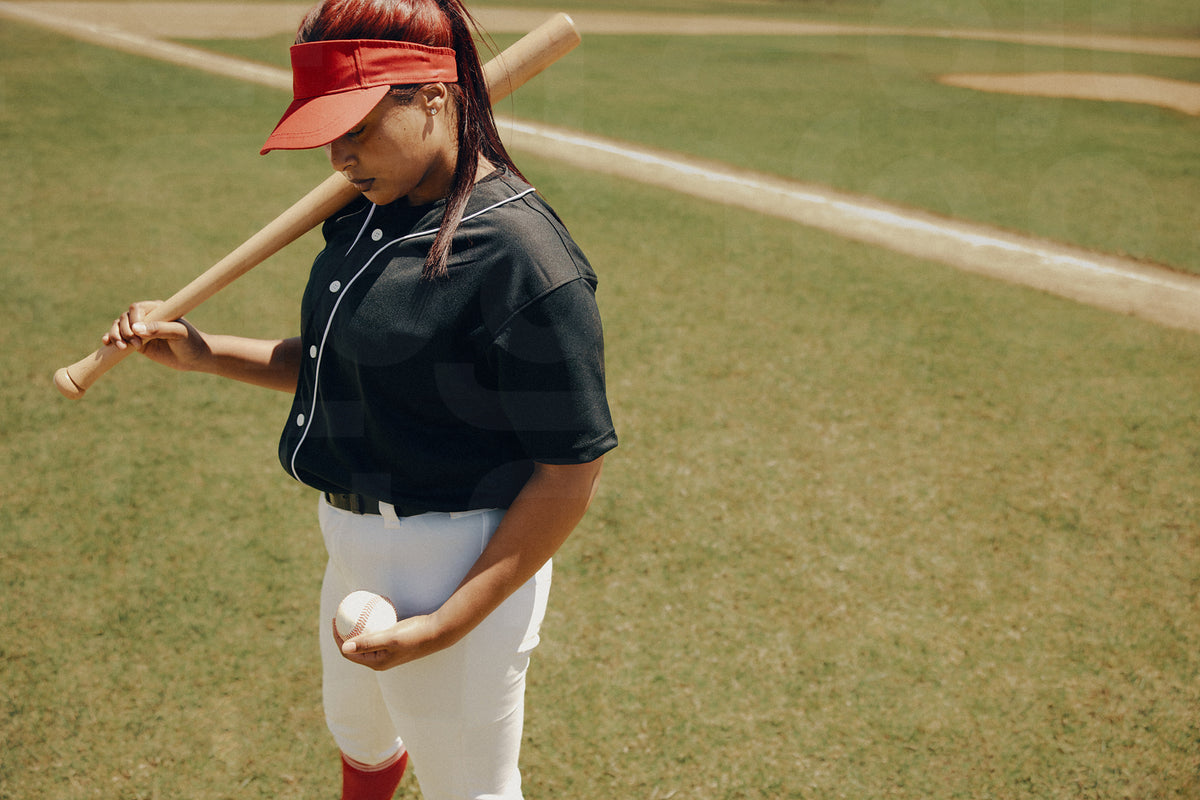 Female baseball league batter standing confidently on the field with a ...