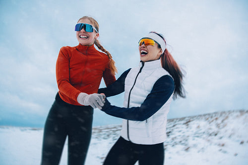 Women enjoy running with friendship and playful energy in winter