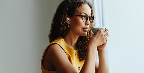 Sipping coffee while pausing during remote work at the window