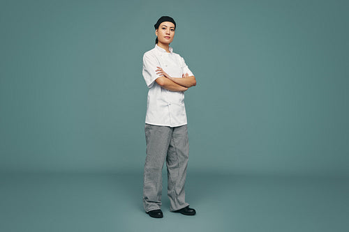 Confident cook standing with her arms crossed in a studio