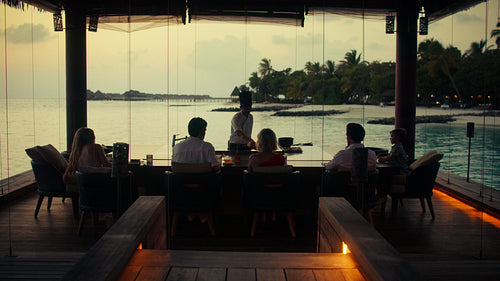 Family enjoying a luxurious culinary experience with a private chef and stunning ocean views at sunset