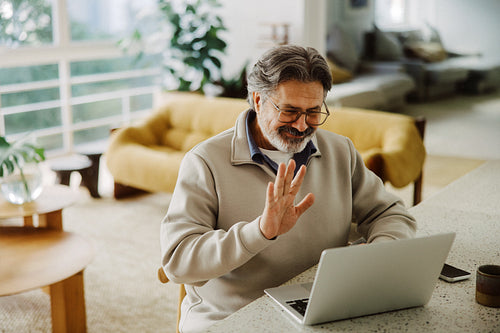 Senior man connects with family on a laptop at home