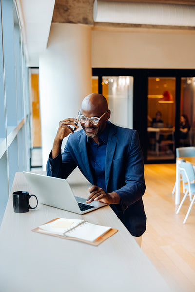 Professional man working on laptop and talking on the phone in an office