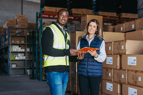 Logistics employees smiling at the camera in a warehouse