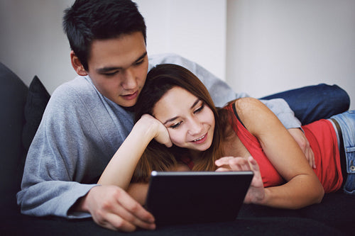 Lovely teenage couple using tablet PC on sofa