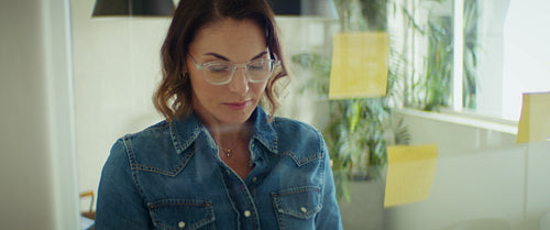 Businesswoman analyzes notes on a glass wall in her office