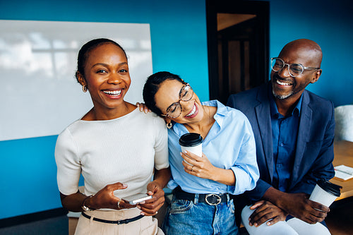 Three colleagues enjoying a break with coffee in a bright office space