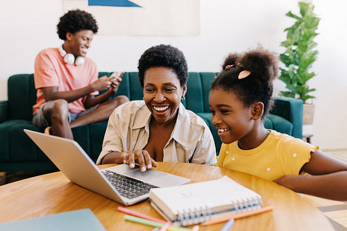 Mother and daughter engaged in home learning with a laptop