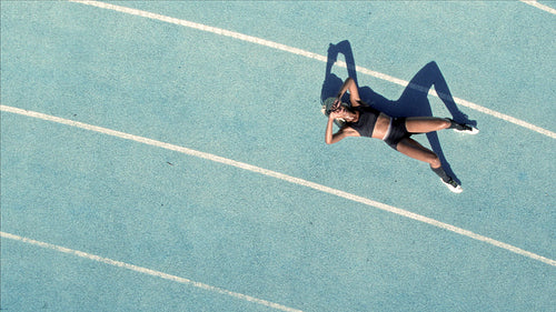 Tired female athlete resting on racetrack