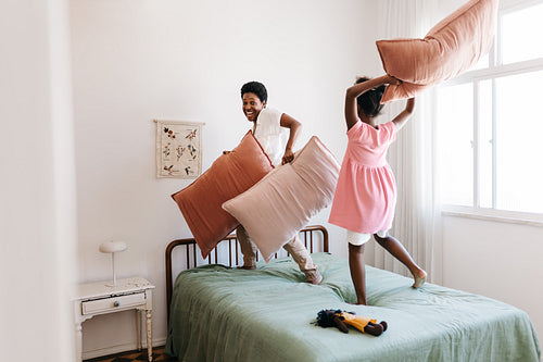 Mom and daughter tossing pillows in a playfyul fight