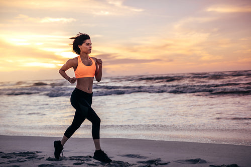 Woman athlete running along the beach in morning