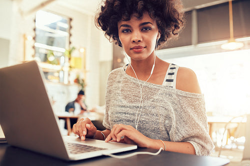 African woman sitting in coffee shop with a laptop