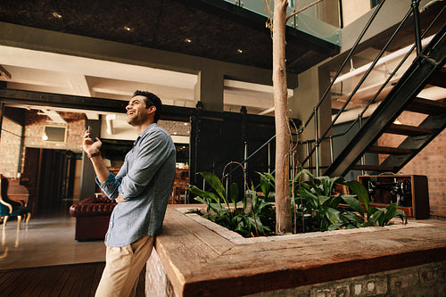 Man standing in modern office with mobile phone
