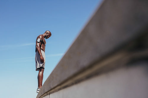 Shirtless young man standing on a wall