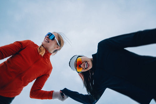 Smiling women are running together in winter snow and cold air