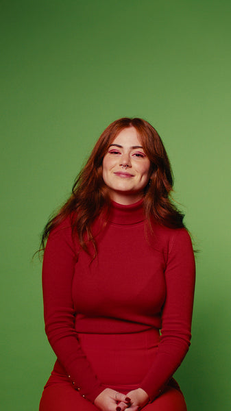 Young woman with long red hair laughs and smiles on a green screen background