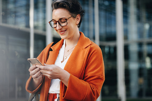 Happy business woman reading a text message on her phone while commuting to work in the city