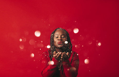 Senior woman blowing confetti into the air in a studio