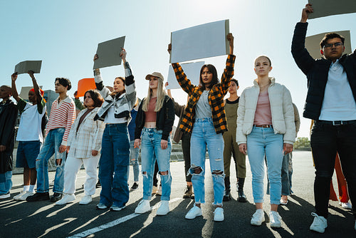 Diverse group of young adults holding signs outdoors during a protest