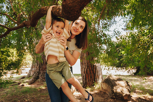 Mother and child playing together on a tree in a park
