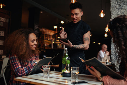 Happy young women giving order to the waiter
