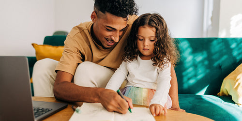 Loving single father teaching his daughter how to draw at home