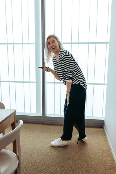Smiling woman holding a smartphone in a bright office space