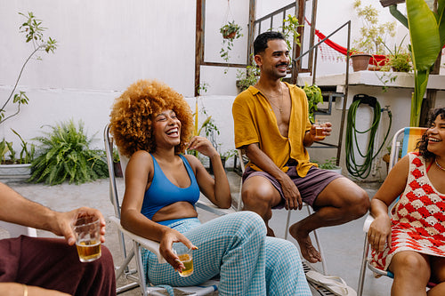 Brazilian friends laughing and drinking beer together at rooftop barbecue in Rio de Janeiro