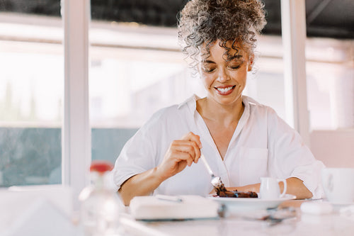 Cheerful mature woman eating some cake in a cafe