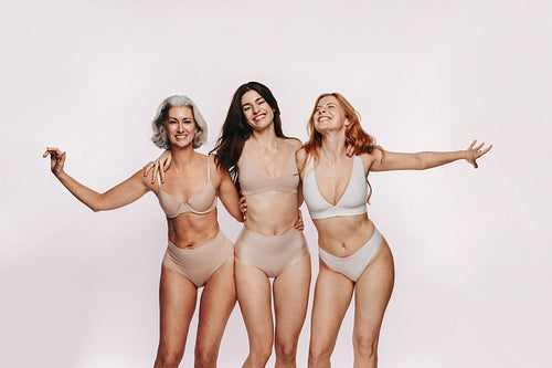 Three women in studio embracing wearing nude lingerie