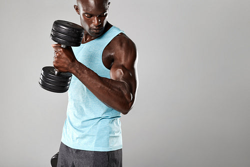 Fit and young man working out with dumbbells