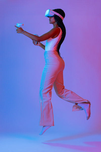 Young woman jumping mid air while playing a virtual reality game