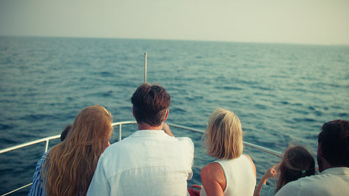 People on a boat watching wild dolphins play and swim in the blue ocean