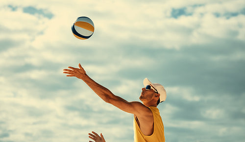 Pro volleyball player soars mid-air, blocking ball during championship game on beach
