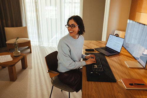 Smiling woman works at a desk in a bright office with a computer