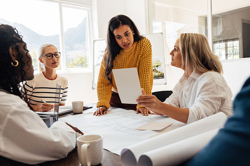 Female architects working together on designs at a desk in a bright office.